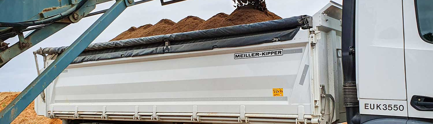 Bagger lädt fruchtbaren Mutterboden auf einen LKW für den Transport zu einer Baustelle in Zülpich.