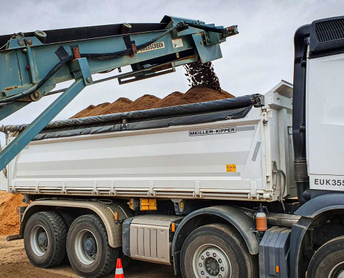 Bagger lädt fruchtbaren Mutterboden auf einen LKW für den Transport zu einer Baustelle in Zülpich.