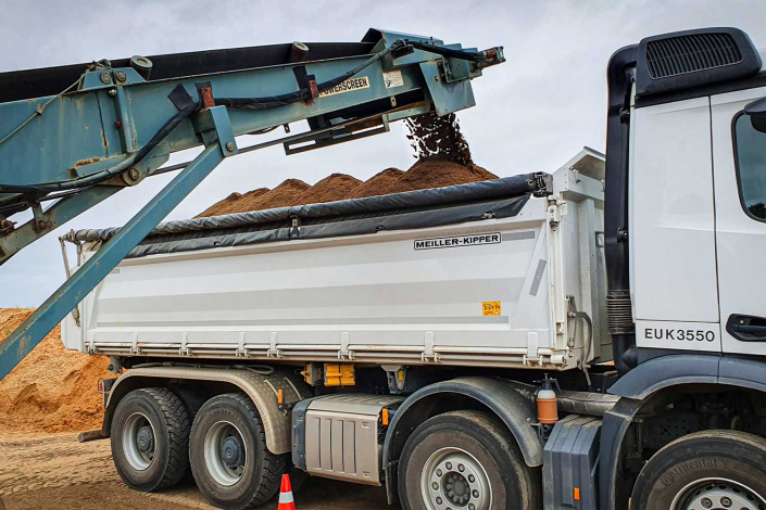 Bagger lädt fruchtbaren Mutterboden auf einen LKW für den Transport zu einer Baustelle in Zülpich.