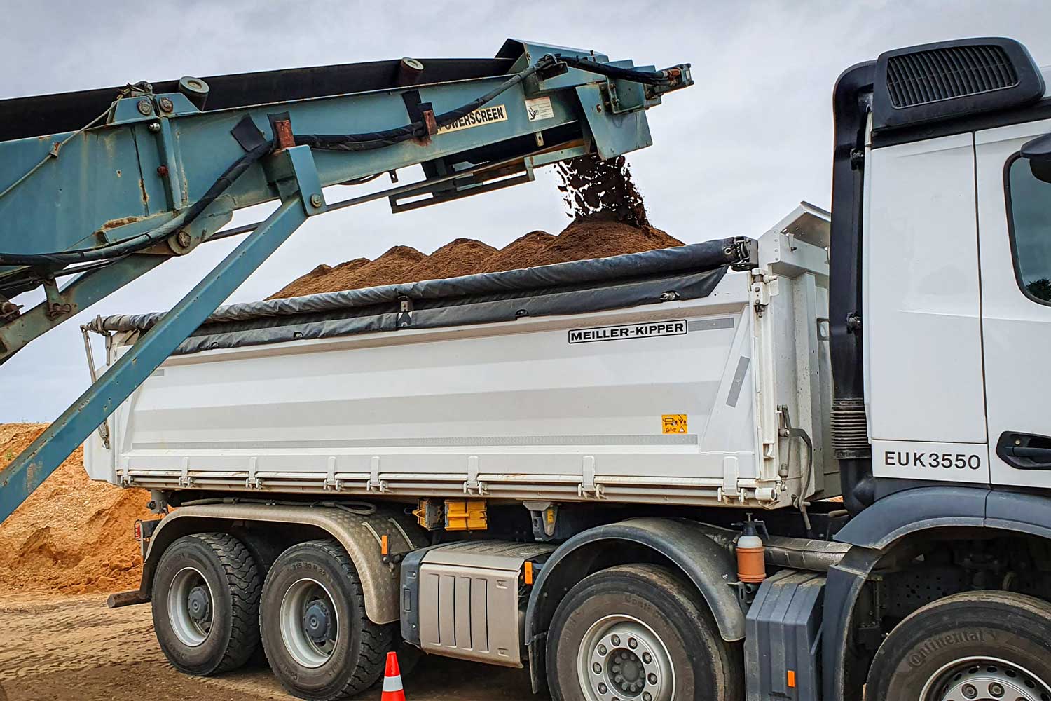 Bagger lädt fruchtbaren Mutterboden auf einen LKW für den Transport zu einer Baustelle in Zülpich.